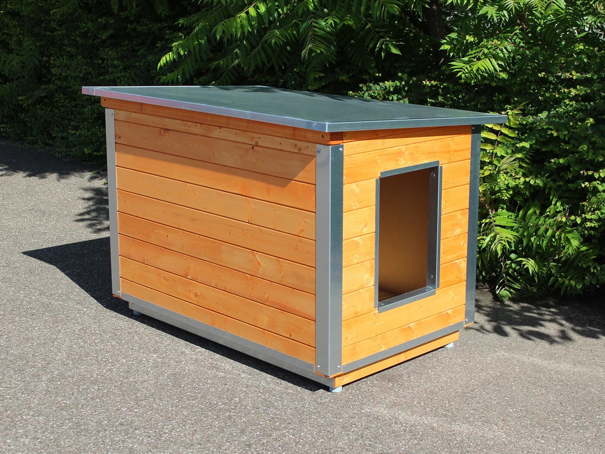 Gestrichene Hundehütte aus Holz im Farbton Kastanie aufgebaut im Garten