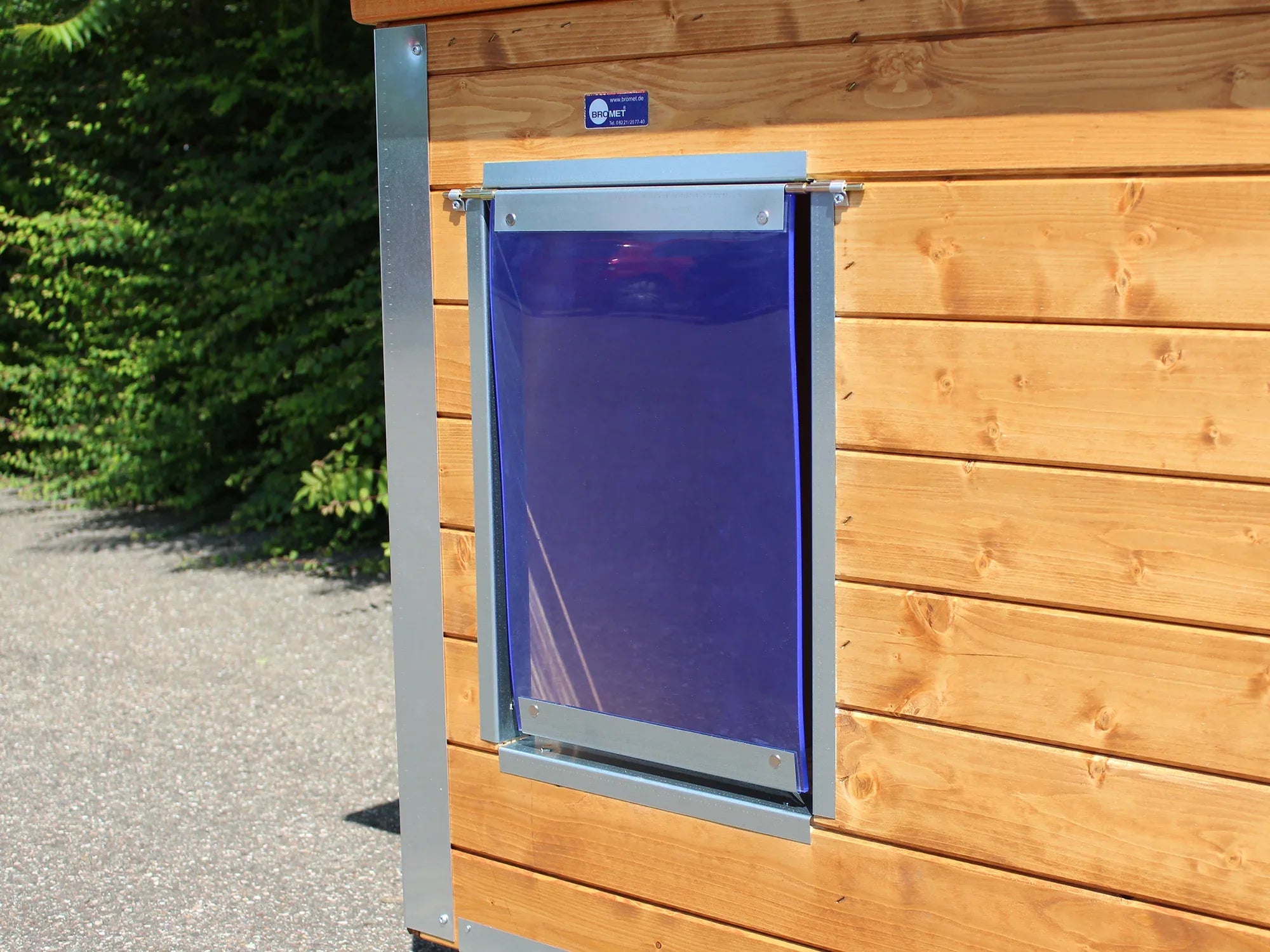 Hundehütte mit geschütztem Eingang durch eine blaue Pendelklappe