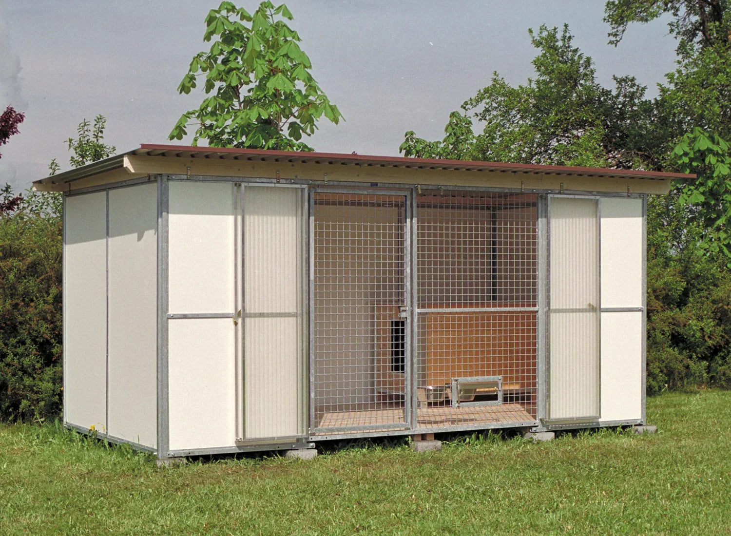 Hundezwinger mit weißen Wänden und einer verschließbaren Vorderseite und einer Hundehütte im inneren