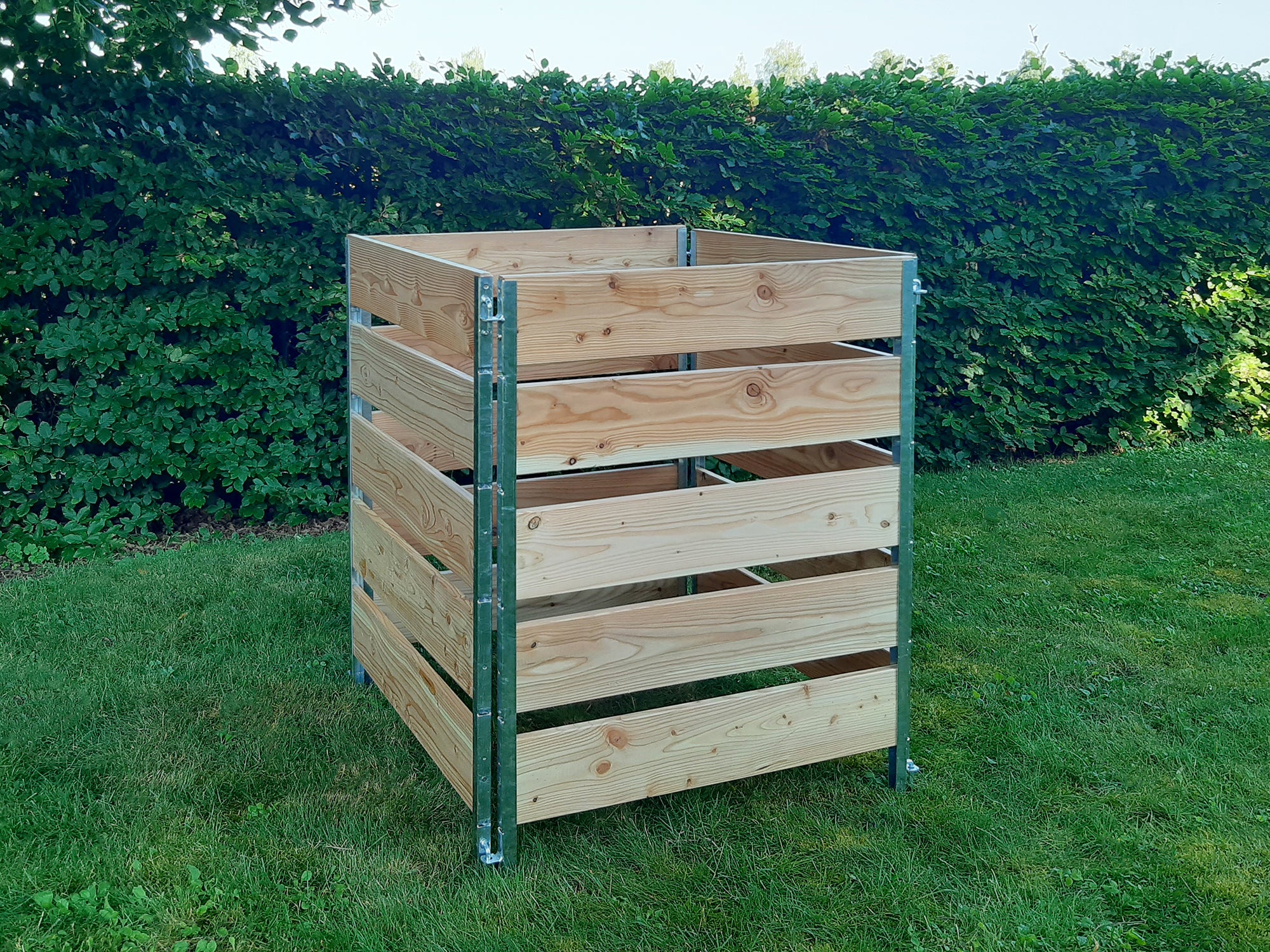 Quadratischer Komposter 1 m hoch stehend im Garten vor einer Hecke