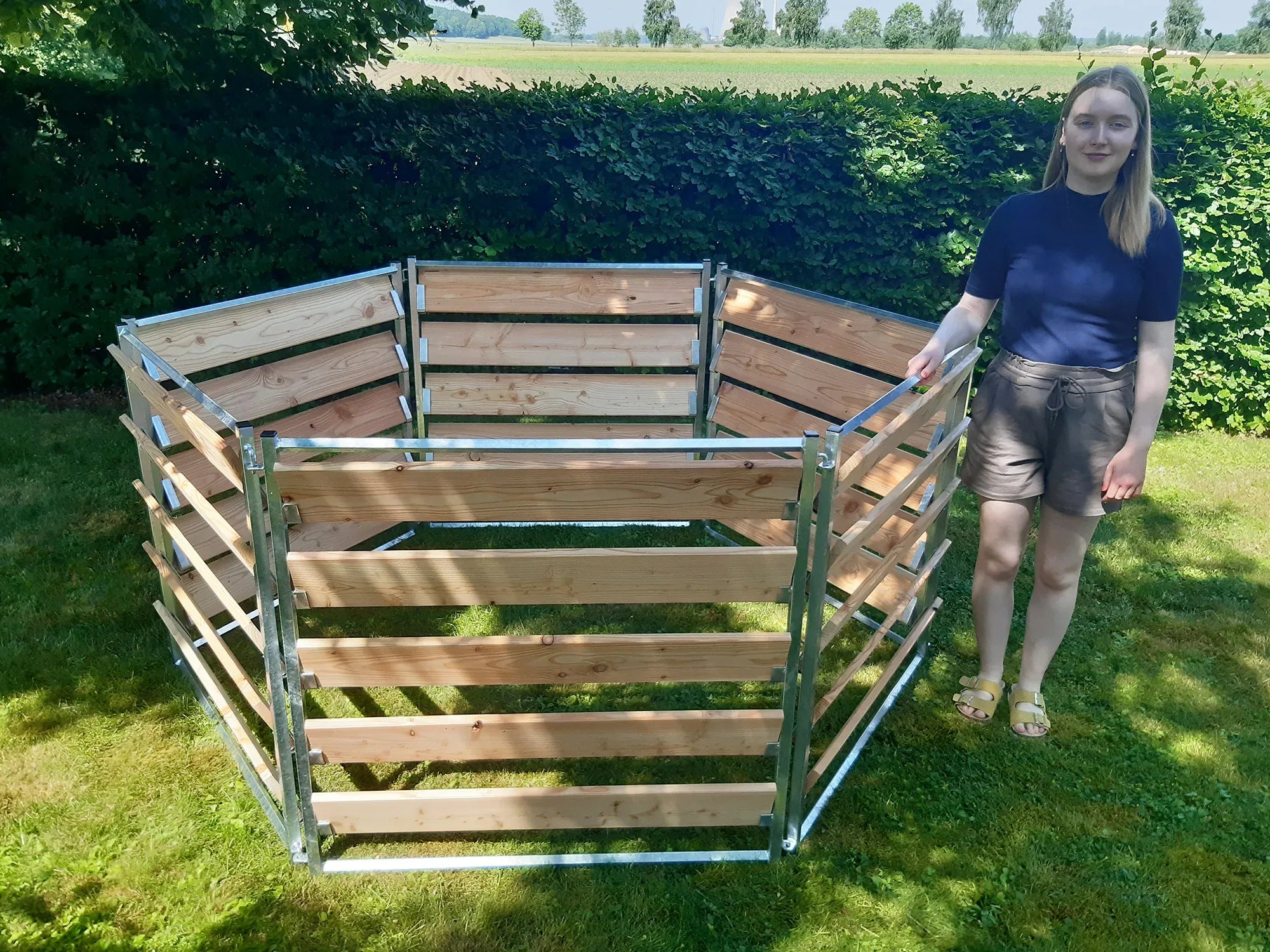 Komposter mit eingesteckten Lärchenbretter aufgebaut im Garten