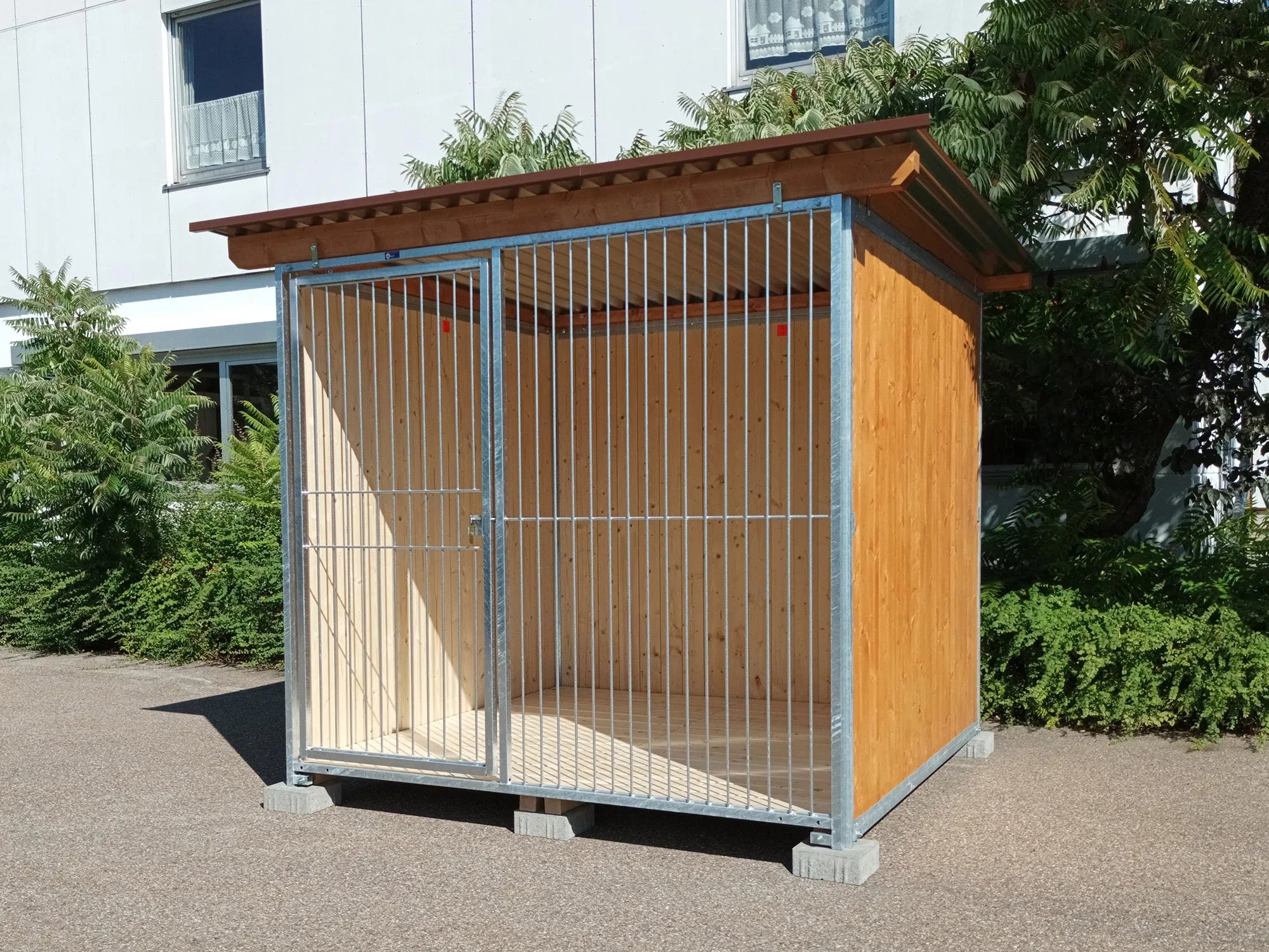 Hundezwinger mit gestrichenen Holzwänden aufgestellt auf Fundamentsteinen