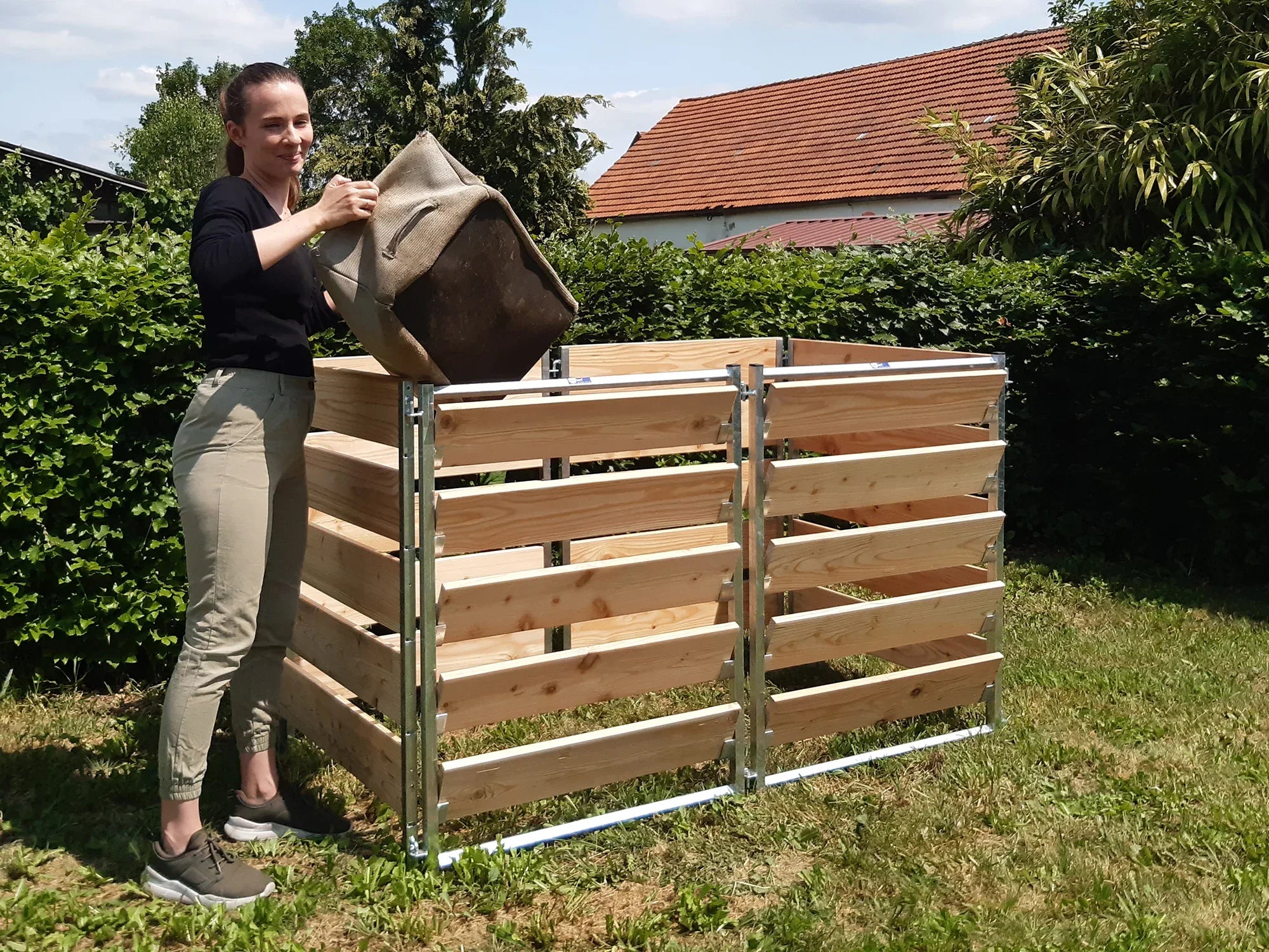 Komposter aus Holz mit Metallrahmen stehend im Garten