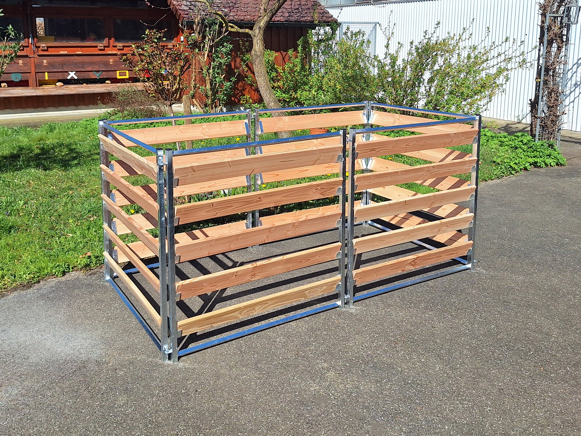 Komposter mit Metallrahmen und Holzbrettern aus Douglasie, aufgebaut im Garten 