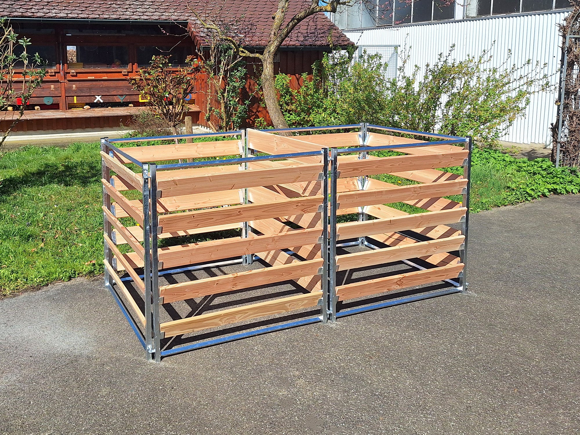 Komposter mit Metallrahmen und Holzbrettern aus Lärche, aufgebaut im Garten 